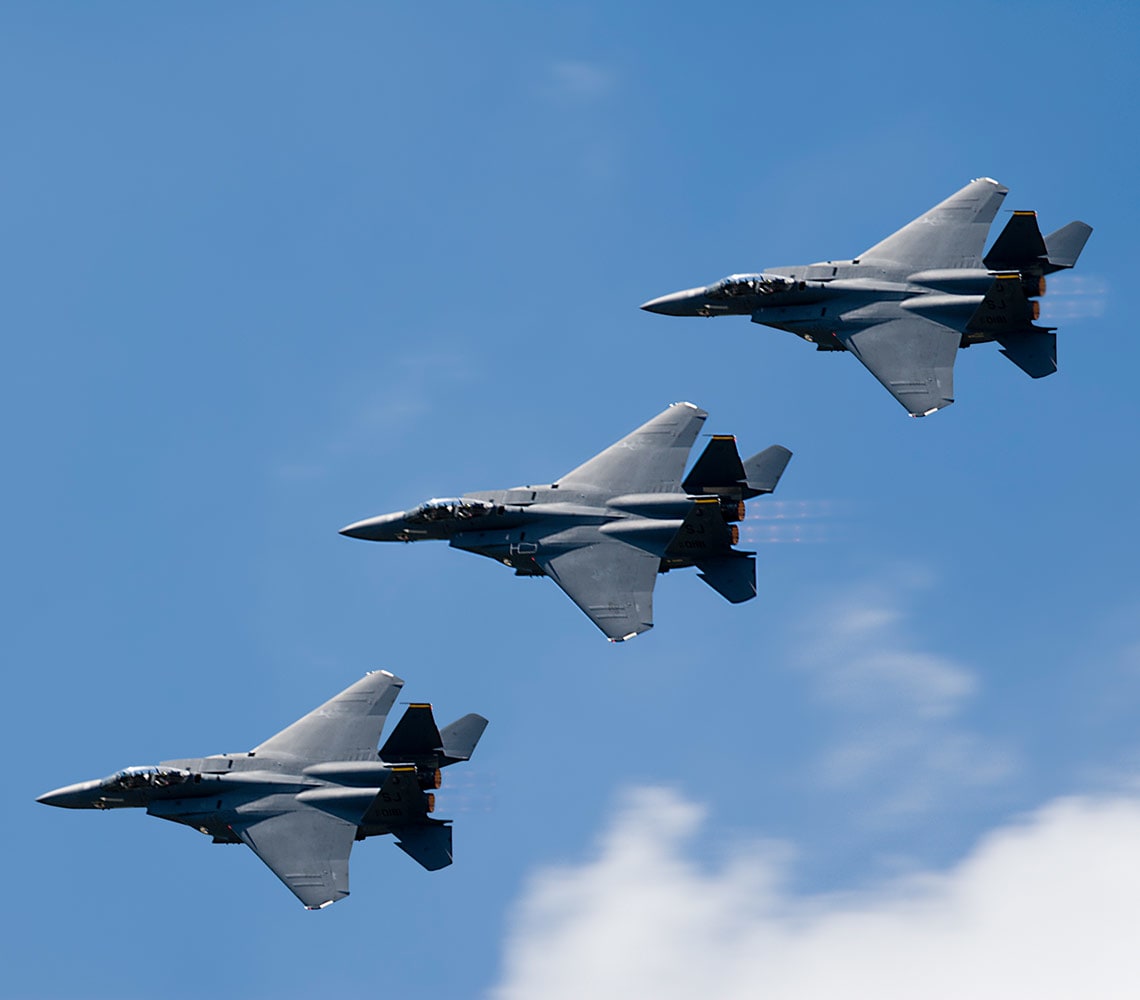 Three fighter jets flying in a precise formation against a clear blue sky.